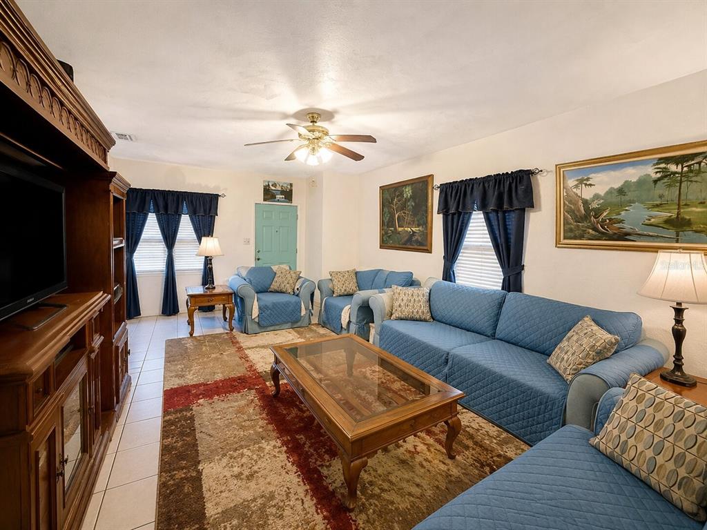 A living room features blue furniture, a patterned area rug, and a wooden entertainment center — 1517 N GRANDVIEW AVENUE, DAYTONA BEACH, FL