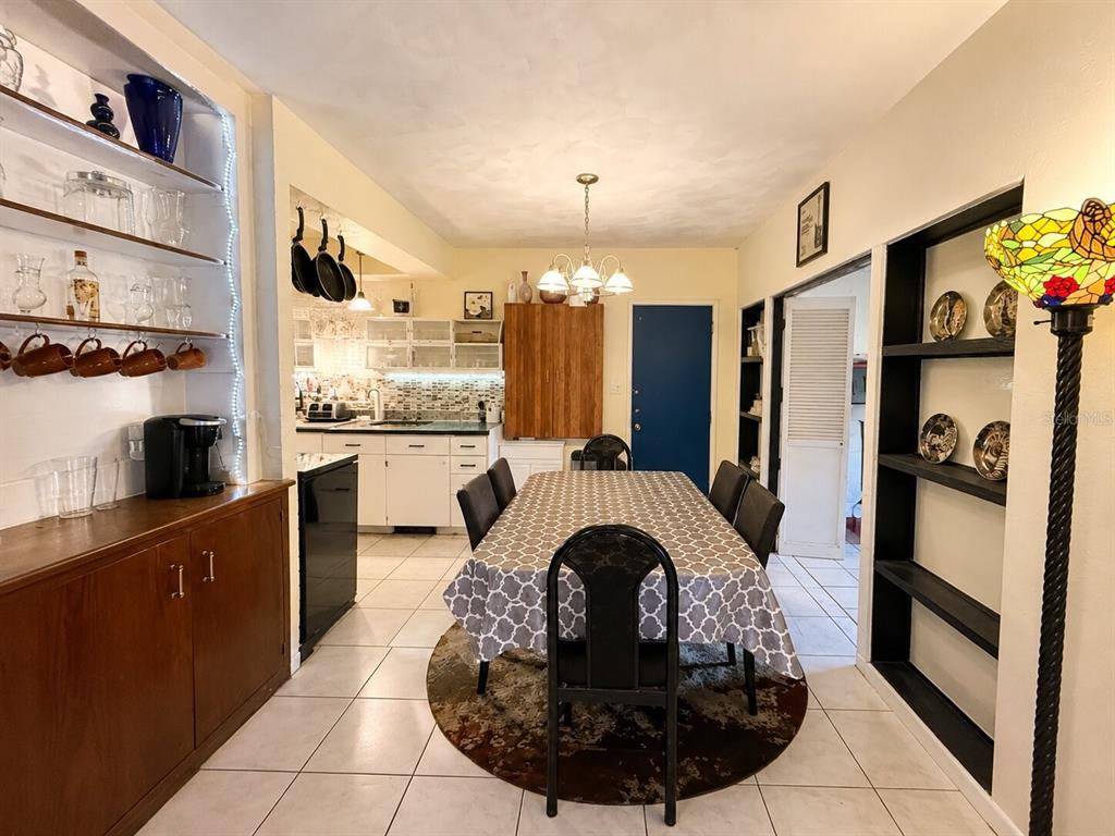 A dining room with a patterned tablecloth, black chairs, and an adjacent kitchen with white cabinets — 1517 N GRANDVIEW AVENUE, DAYTONA BEACH, FL