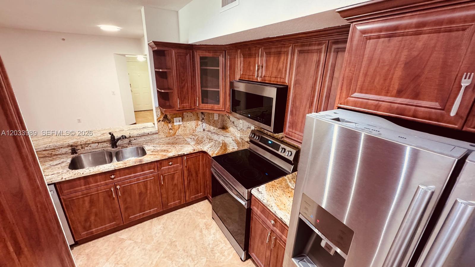 A kitchen features cherry wood cabinets, granite countertops, and stainless steel appliances — 2516 Centergate Dr # 102, Miramar FL 33025, MIRAMAR, FL