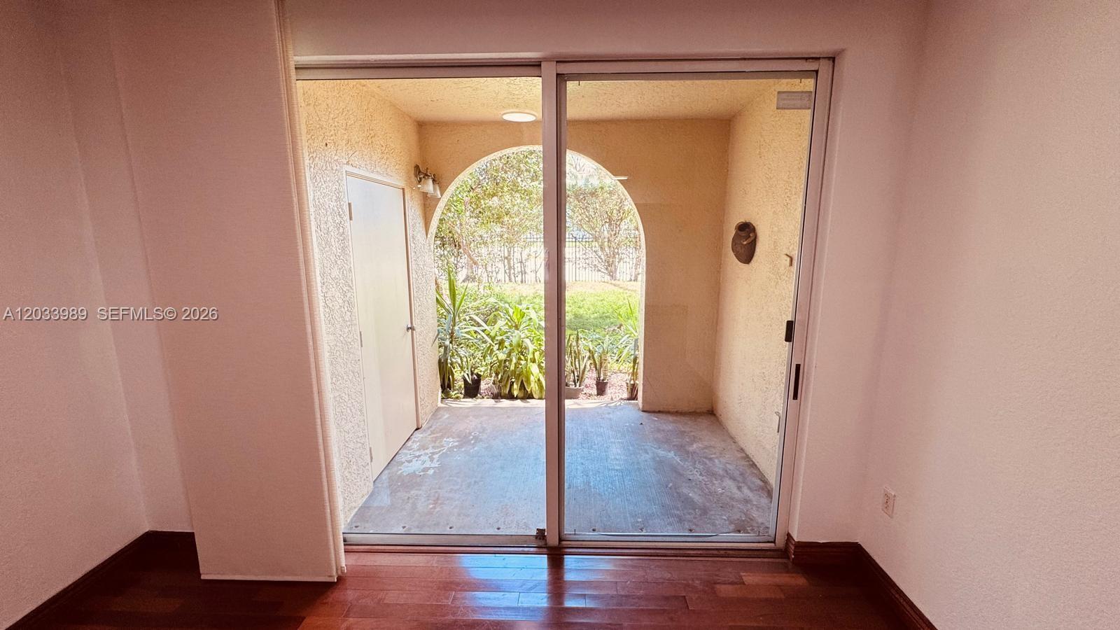 A sliding glass door opens to a covered patio with an arched entryway and plants — 2516 Centergate Dr # 102, Miramar FL 33025, MIRAMAR, FL