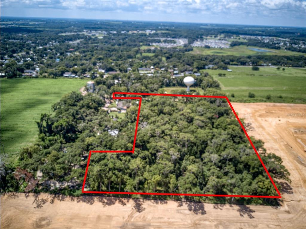 An aerial view shows a wooded plot of land outlined in red near a water tower — SKYLINE DRIVE, DADE CITY, FL