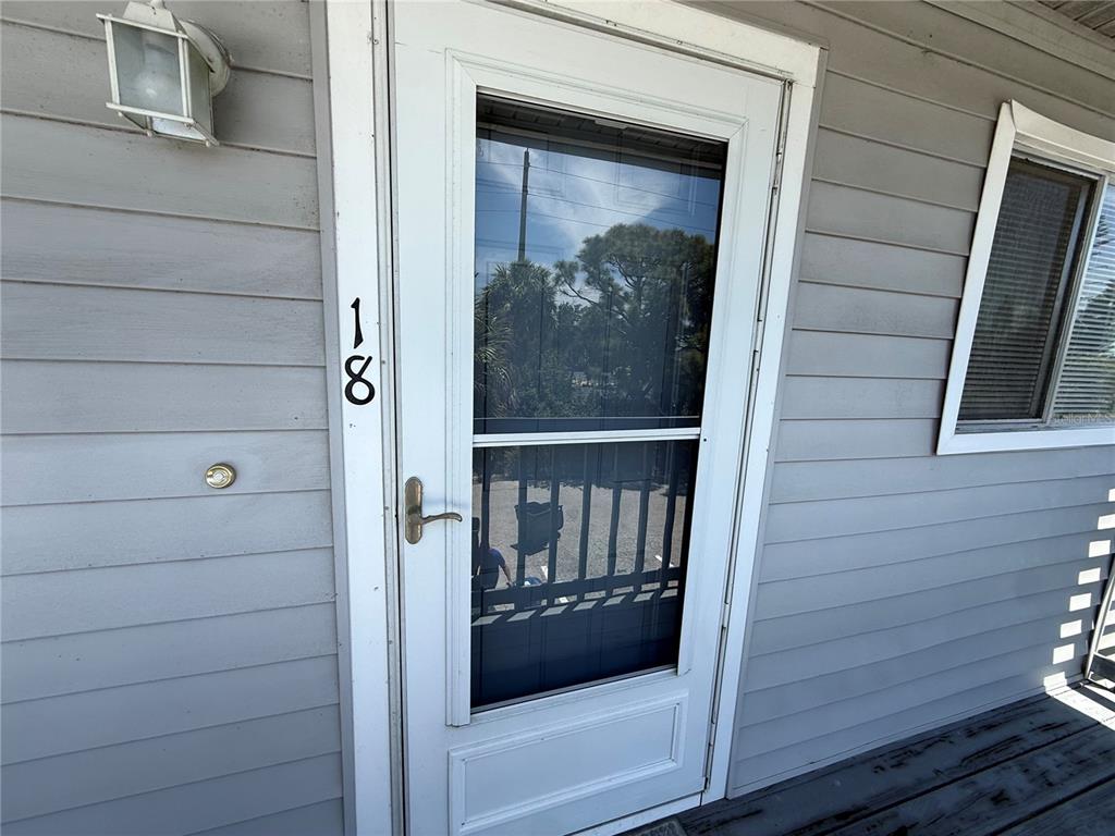 A white storm door with the number 18 on the siding is shown — 255 FENWICK DRIVE UNIT 18, VENICE, FL