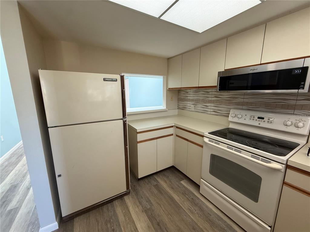 A kitchen features white appliances, light-colored cabinetry, and wood-look flooring — 255 FENWICK DRIVE UNIT 18, VENICE, FL