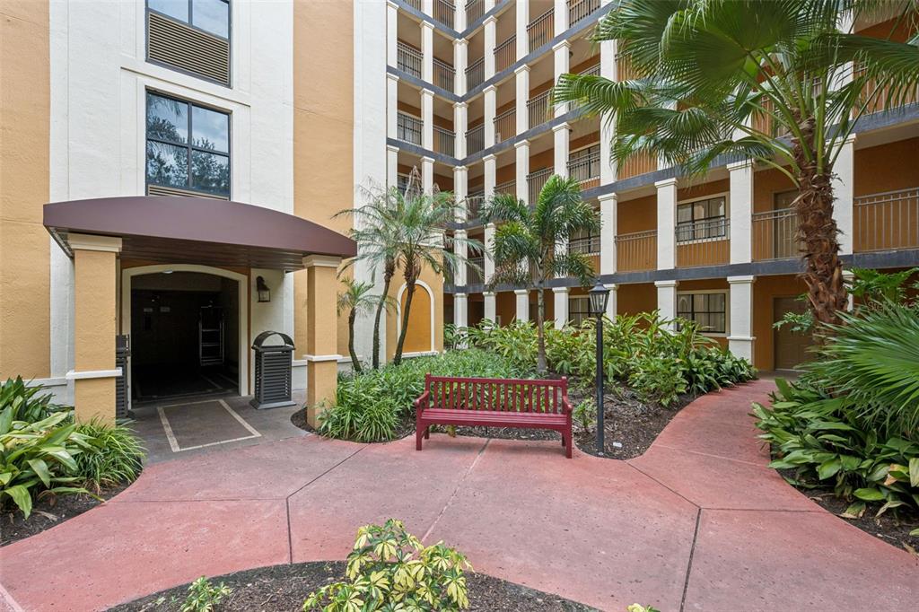 A red bench sits on a paved walkway in front of a multi-story apartment building — 12538 FLORIDAYS RESORT DRIVE UNIT 109C, ORLANDO, FL