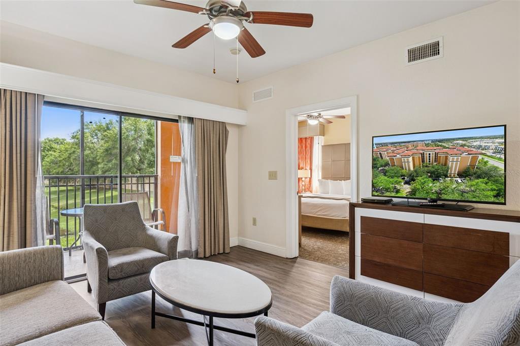 A living room with a ceiling fan, sliding glass doors, and a view into a bedroom — 12538 FLORIDAYS RESORT DRIVE UNIT 109C, ORLANDO, FL