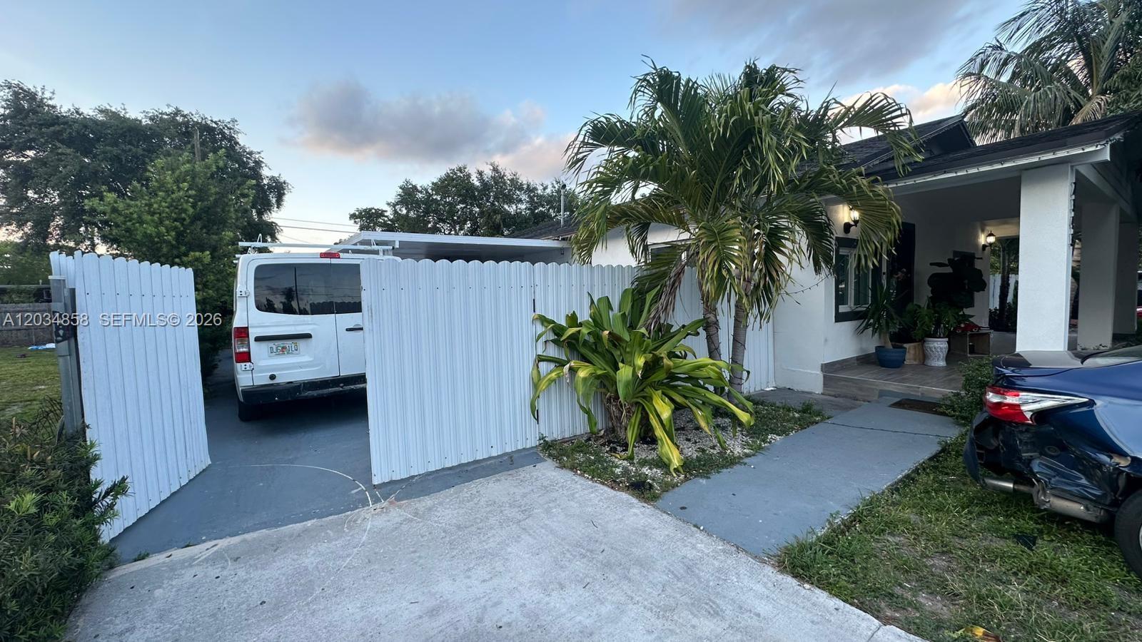 A white van is parked behind a white fence next to a house with a palm — 2343 NW 102nd St, Miami FL 33147, MIAMI, FL