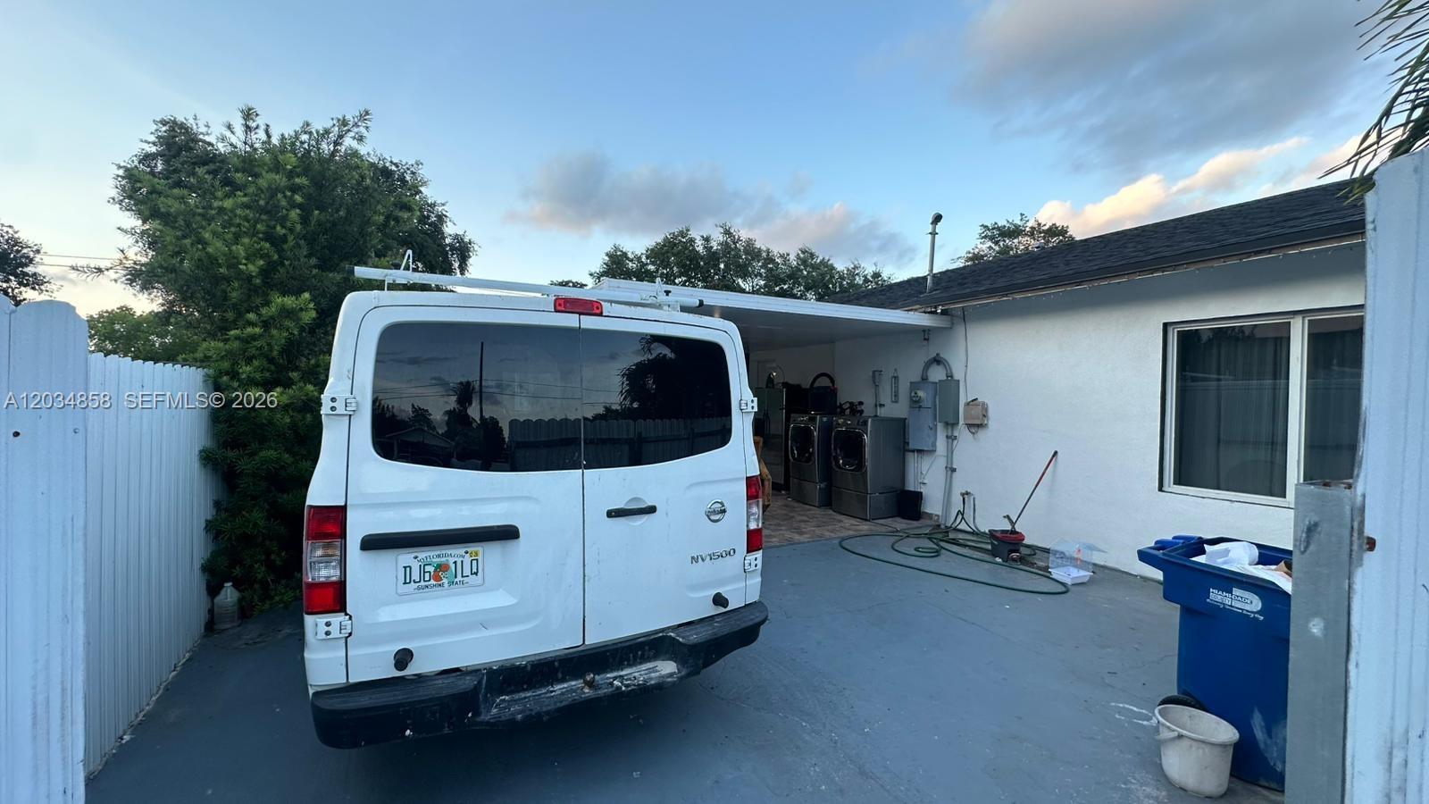 A white Nissan van is parked in a paved driveway next to a house exterior — 2343 NW 102nd St, Miami FL 33147, MIAMI, FL