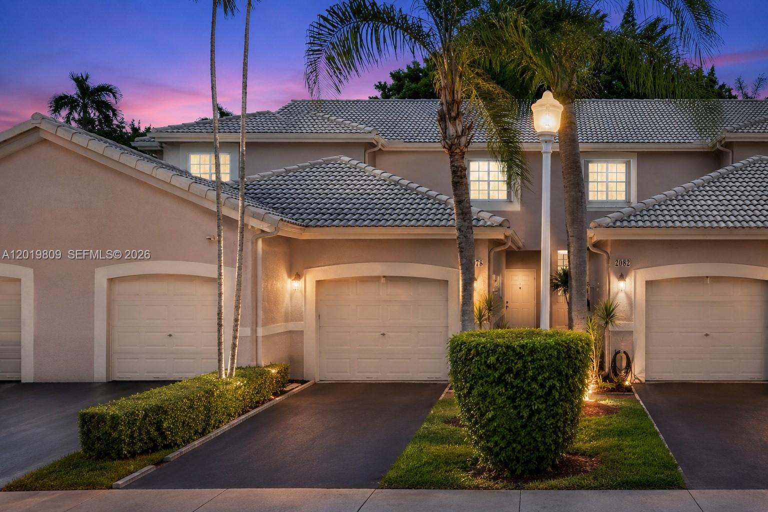 This exterior view shows a two-story townhouse with a beige stucco facade and tiled roof — 2078 Madeira Dr # 0, Weston FL 33327, WESTON, FL