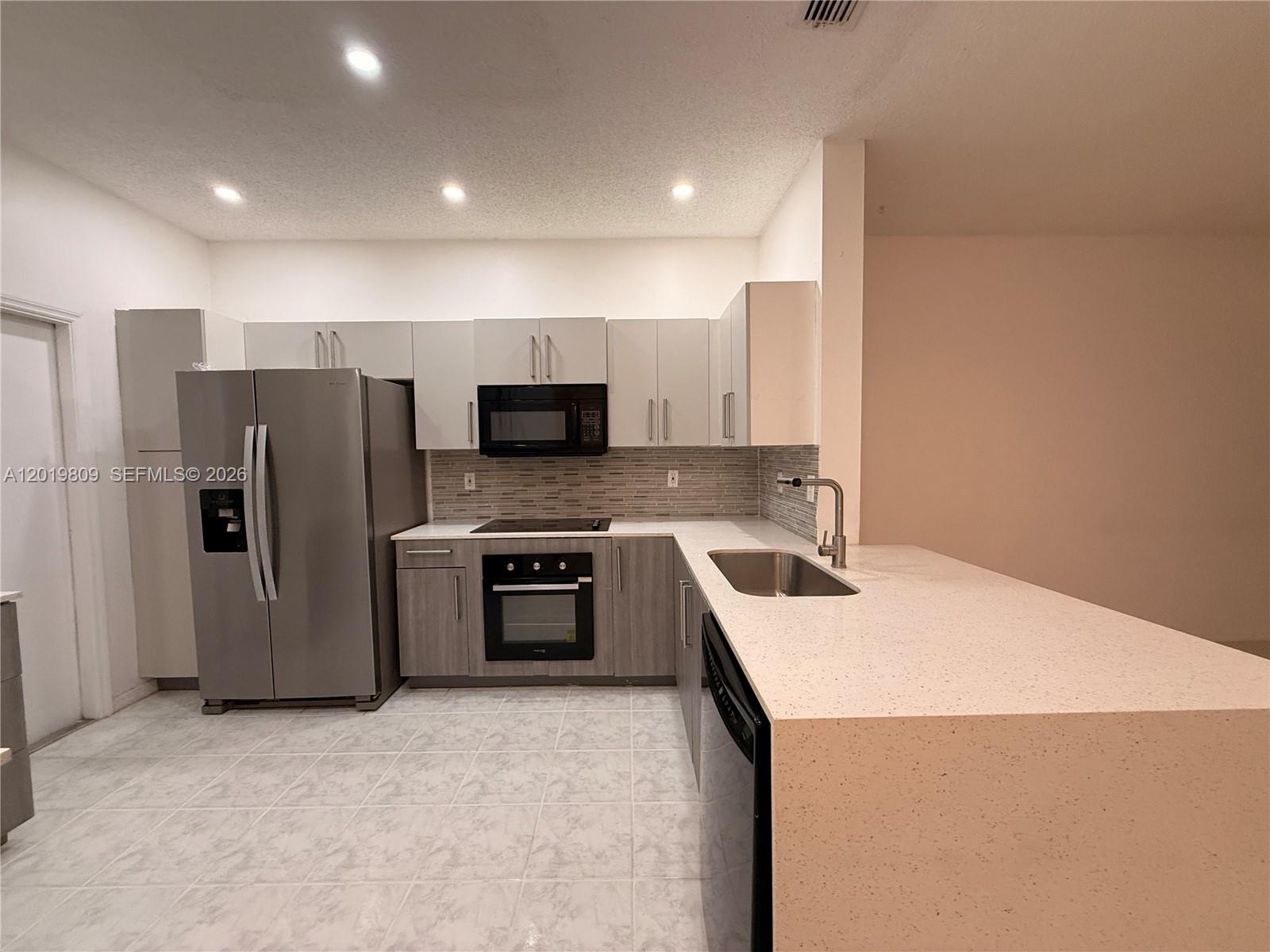 A kitchen features stainless steel appliances, light-colored cabinetry, and a white quartz countertop peninsula — 2078 Madeira Dr # 0, Weston FL 33327, WESTON, FL