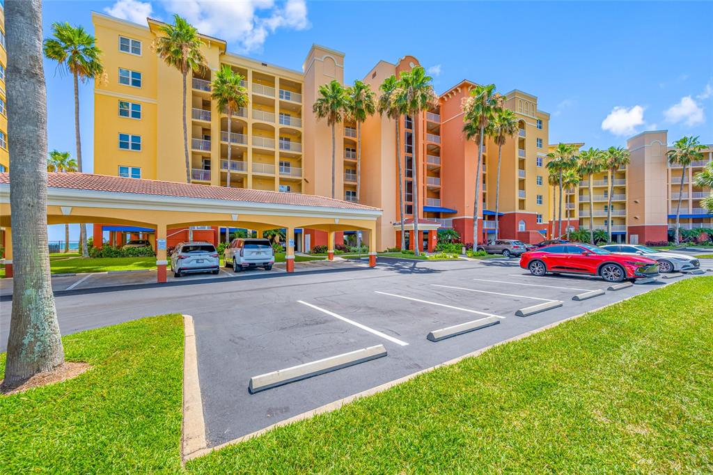 A multi-story apartment building with a covered parking area and palm trees in the foreground — 16550 GULF BOULEVARD UNIT 645, NORTH REDINGTON BEACH, FL