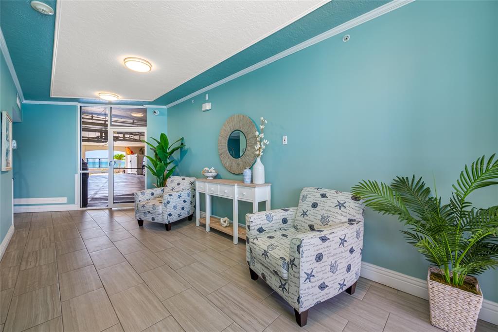 A coastal-themed lobby features two patterned armchairs, a white console table, and tile flooring — 16550 GULF BOULEVARD UNIT 645, NORTH REDINGTON BEACH, FL