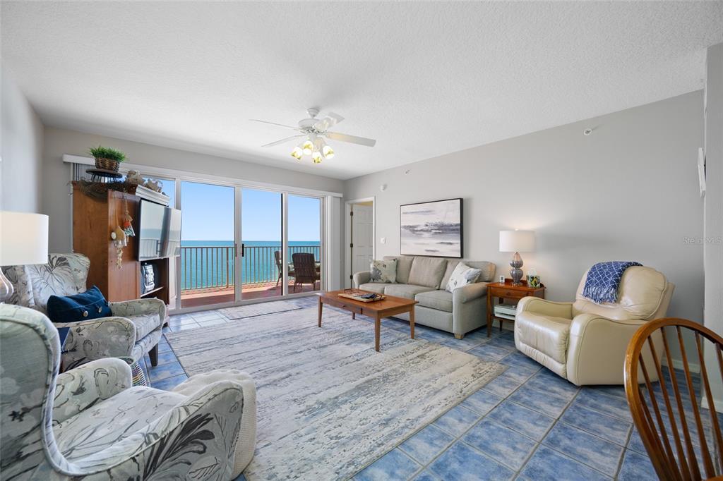 A living room with tile floors, a sofa, armchairs, and a balcony overlooking the ocean — 16550 GULF BOULEVARD UNIT 645, NORTH REDINGTON BEACH, FL