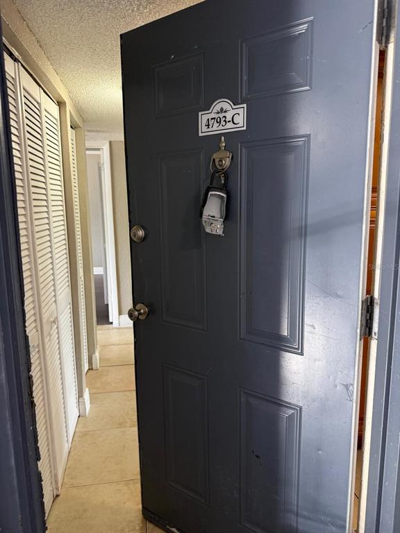 A dark gray door with a lockbox hangs open, revealing a tiled hallway and closet — 4793 S TEXAS AVENUE UNIT 4793C, ORLANDO, FL