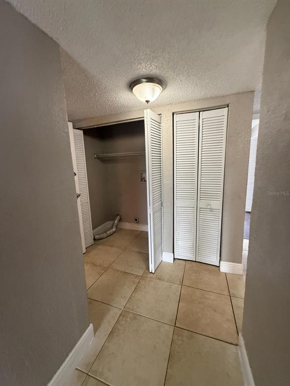 A tiled laundry closet with louvered doors and a ceiling light fixture — 4793 S TEXAS AVENUE UNIT 4793C, ORLANDO, FL