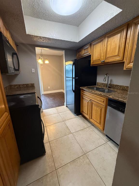 A kitchen features light-colored tile floors, wooden cabinets, black appliances, and a granite countertop — 4793 S TEXAS AVENUE UNIT 4793C, ORLANDO, FL