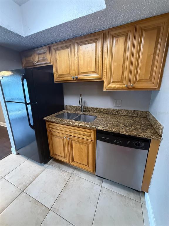 A kitchen features wood cabinets, granite countertops, a stainless steel dishwasher, and a black refrigerator — 4793 S TEXAS AVENUE UNIT 4793C, ORLANDO, FL