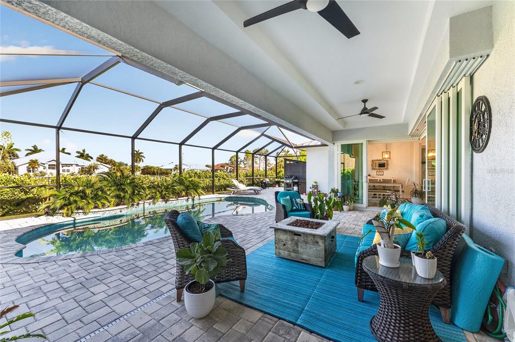 A covered patio features a swimming pool, wicker furniture, and a fire pit — 9305 SPRING CIRCLE, PORT CHARLOTTE, FL