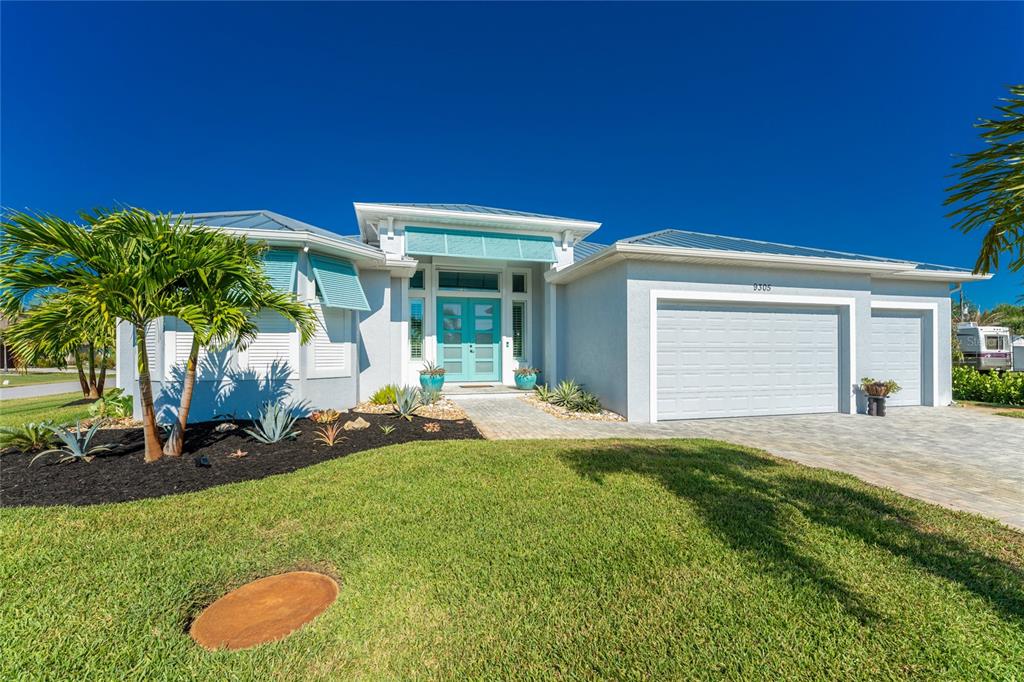 A single-story house with a light gray exterior, teal double doors, and a metal roof — 9305 SPRING CIRCLE, PORT CHARLOTTE, FL