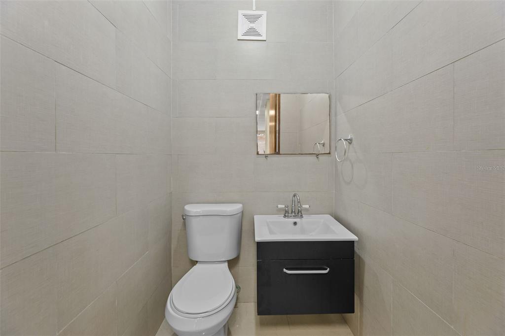 A small bathroom features light-colored wall tiles, a white toilet, and a dark vanity cabinet — 152 C. NÚÑEZ ROMERO UNIT 152, CAYEY, PR