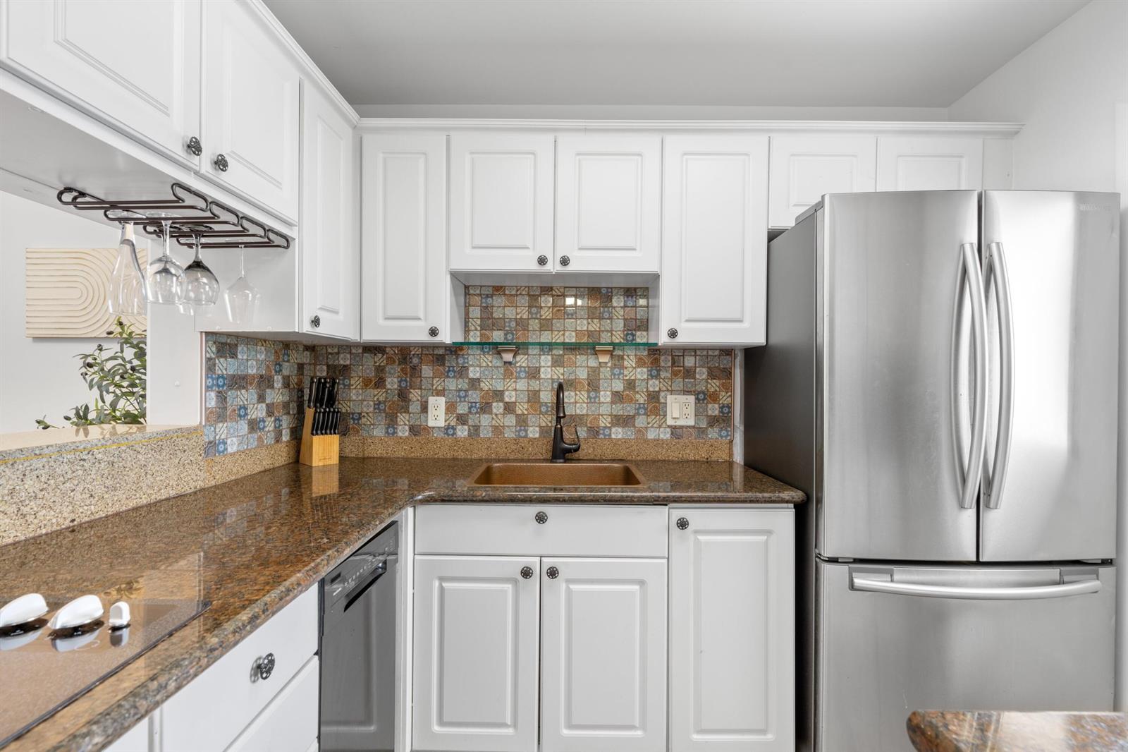 A kitchen with white cabinets, granite countertops, a mosaic tile backsplash, and stainless steel appliances — 5501 NW 2nd Avenue # 2130, Boca Raton FL 33487, BOCA RATON, FL