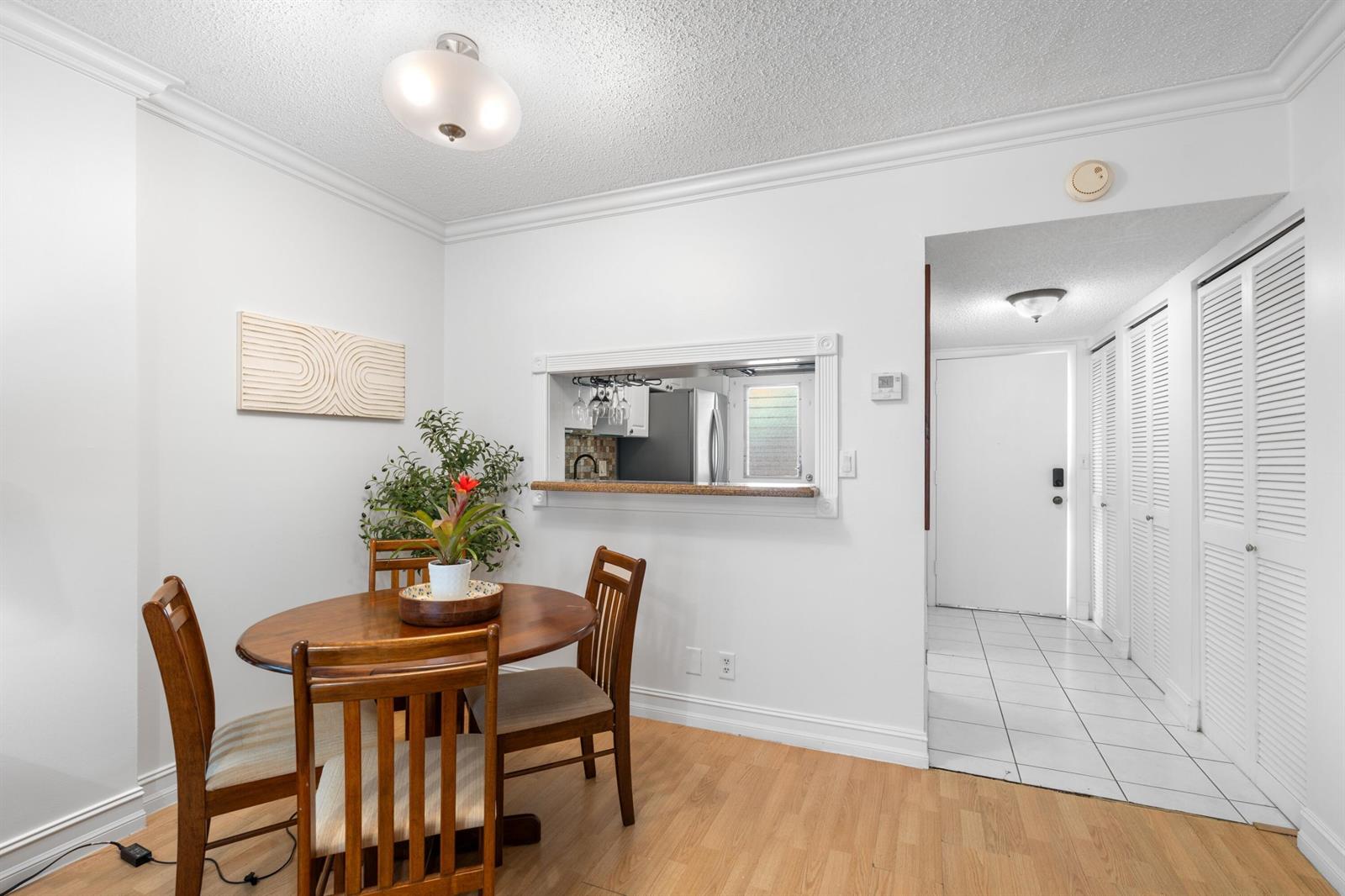 A dining area with a wooden table and chairs, featuring a pass-through window to the kitchen — 5501 NW 2nd Avenue # 2130, Boca Raton FL 33487, BOCA RATON, FL