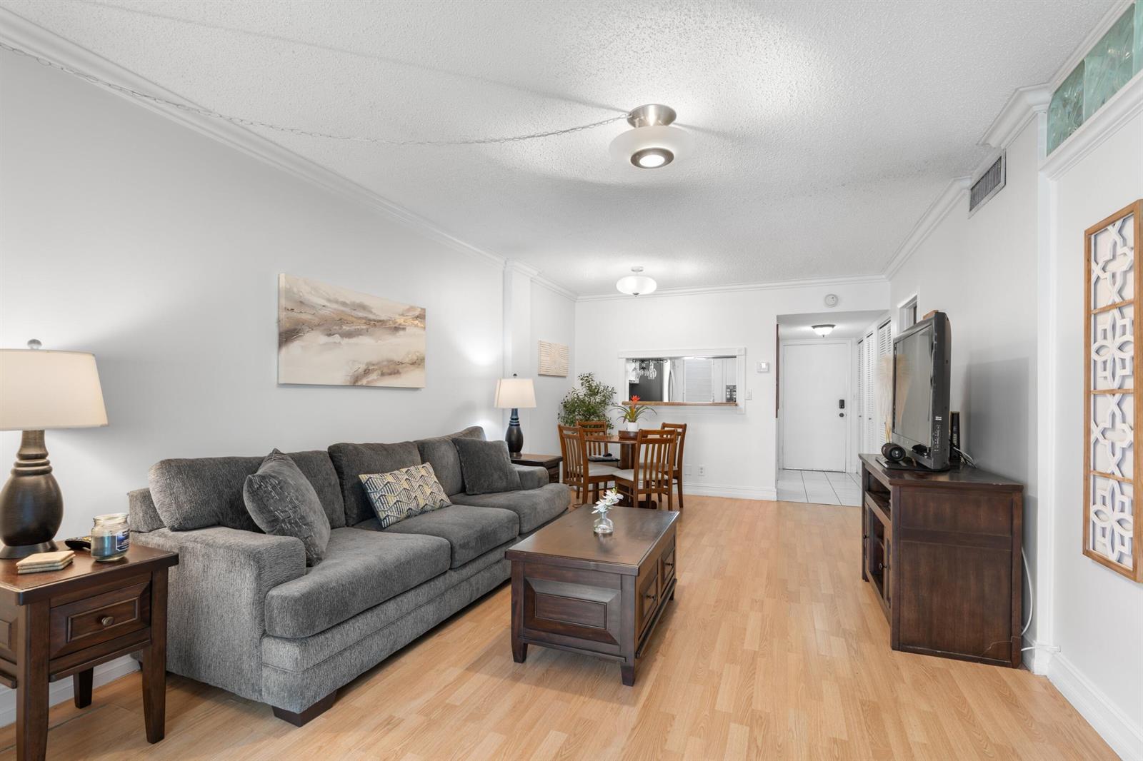A living room features a gray sofa, wooden coffee table, and dining area with light flooring — 5501 NW 2nd Avenue # 2130, Boca Raton FL 33487, BOCA RATON, FL