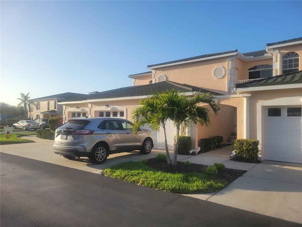 A silver SUV is parked in the driveway of a two-story peach-colored townhouse — 1203 GONDOLA PARK DRIVE UNIT 1203, VENICE, FL