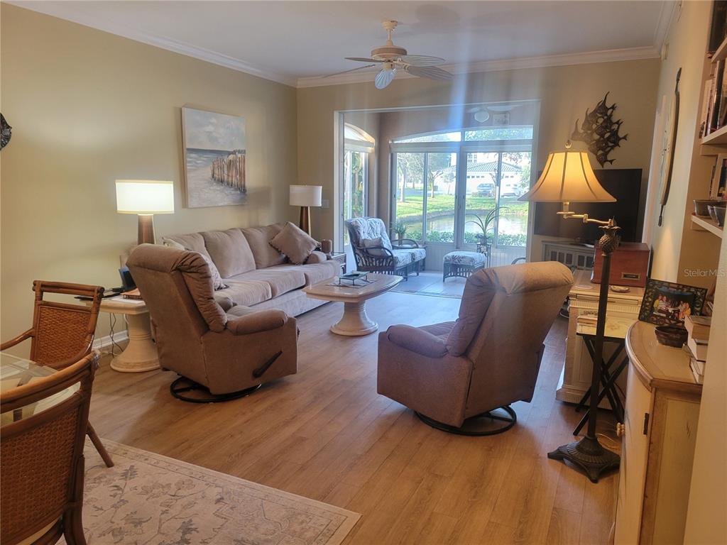 A living room features light wood flooring, a sofa, two recliners, and a screened-in patio — 1203 GONDOLA PARK DRIVE UNIT 1203, VENICE, FL