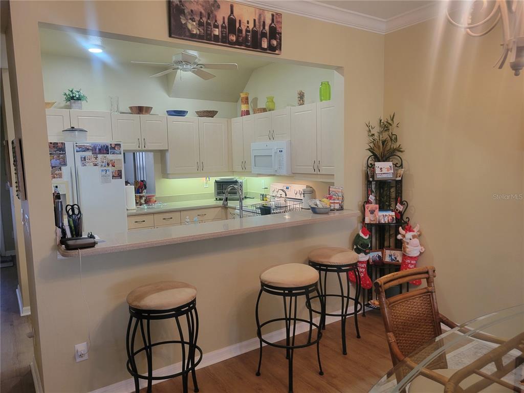 A kitchen with white cabinets and a breakfast bar featuring three stools — 1203 GONDOLA PARK DRIVE UNIT 1203, VENICE, FL