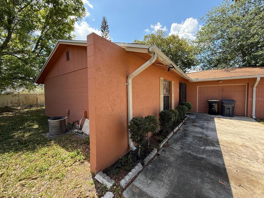 An exterior view of a peach-colored house with a concrete driveway and a garage — 451 CART COURT, POINCIANA, FL