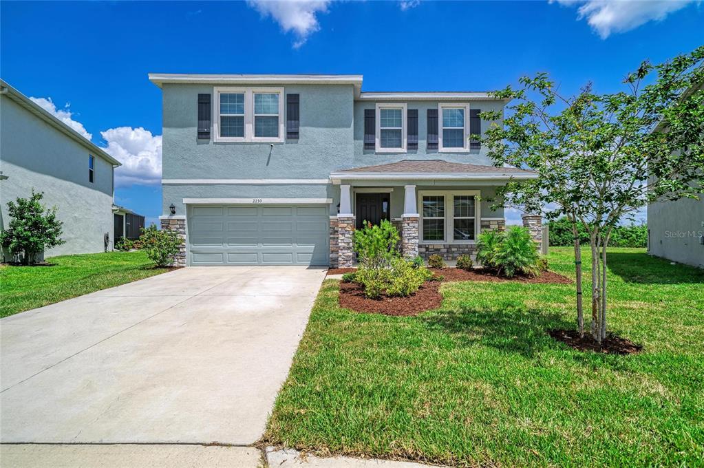 An aerial view of a two-story light blue house with a stone-accented entryway and driveway — 2230 MARSH HARBOUR LOOP, BRADENTON, FL