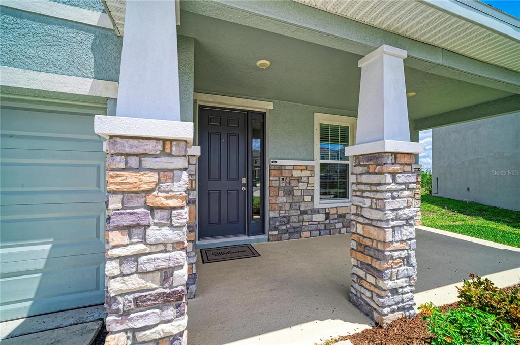 A two-story suburban house with a light blue stucco exterior, stone accents, and a driveway — 2230 MARSH HARBOUR LOOP, BRADENTON, FL