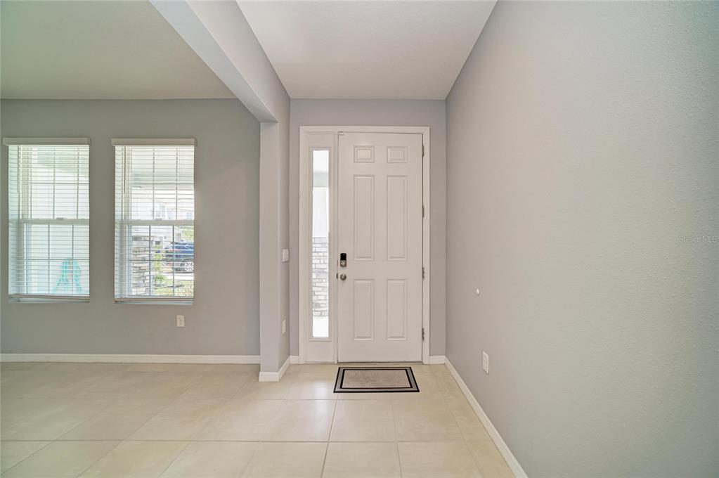 A covered front porch features stone-clad pillars, a dark front door, and a concrete floor — 2230 MARSH HARBOUR LOOP, BRADENTON, FL