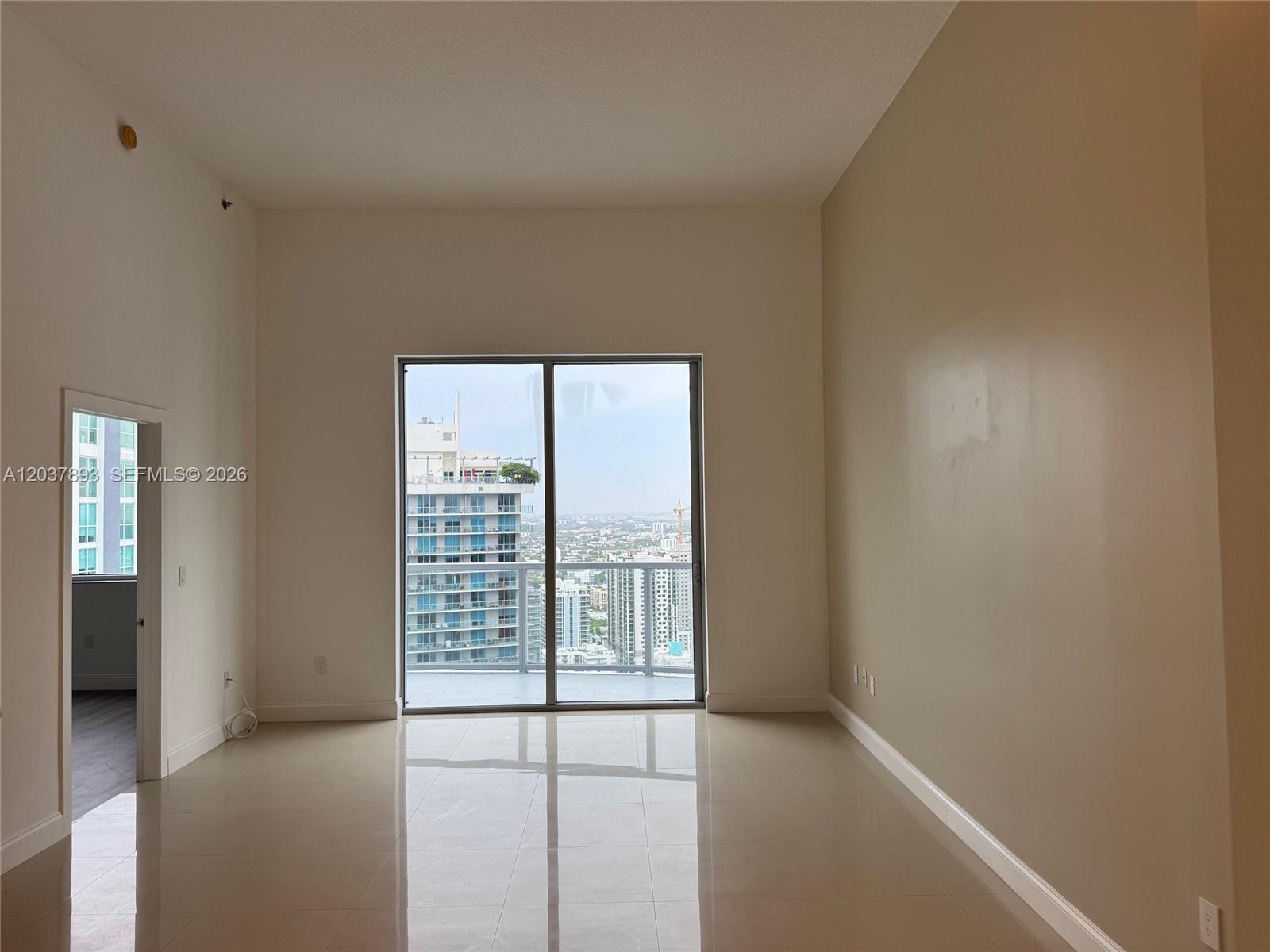 An empty room with light-colored tile flooring, white walls, and a sliding glass balcony door — 1060 Brickell Ave # 4115, Miami FL 33131, MIAMI, FL