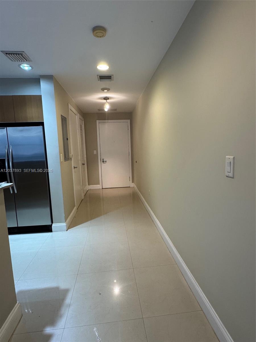 A hallway with light-colored tile flooring leads to a white door — 1060 Brickell Ave # 4115, Miami FL 33131, MIAMI, FL