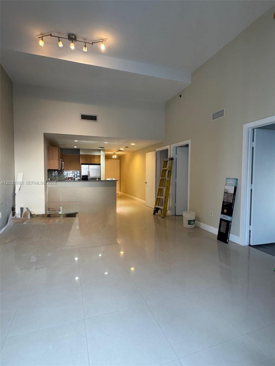 An open-concept living area features light tile flooring, high ceilings, and an adjacent kitchen — 1060 Brickell Ave # 4115, Miami FL 33131, MIAMI, FL