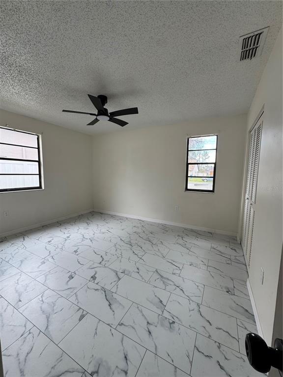 A bedroom with white marble-patterned tile flooring, a ceiling fan, and two windows — 10315 WALTON STREET, SPRING HILL, FL