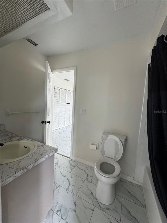 A bathroom features a vanity, a toilet, and a shower with a dark curtain — 10315 WALTON STREET, SPRING HILL, FL