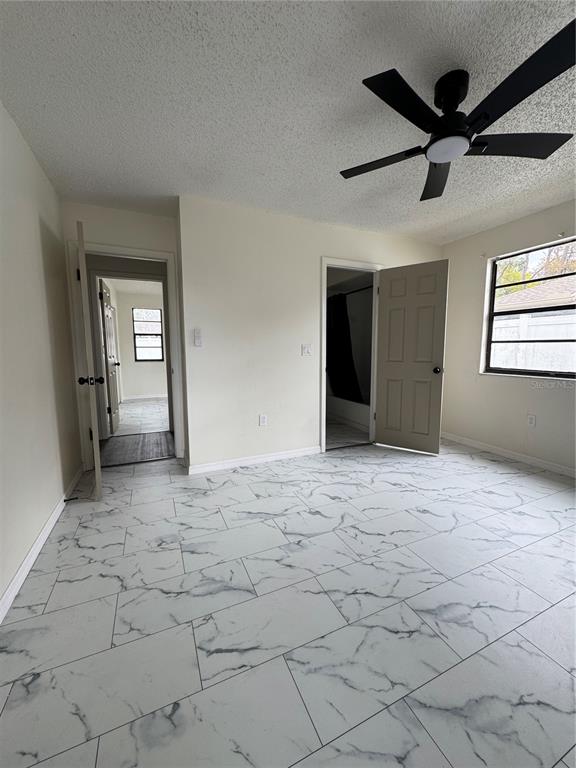 A bedroom features white marble-patterned tile flooring, a ceiling fan, and two open doorways — 10315 WALTON STREET, SPRING HILL, FL