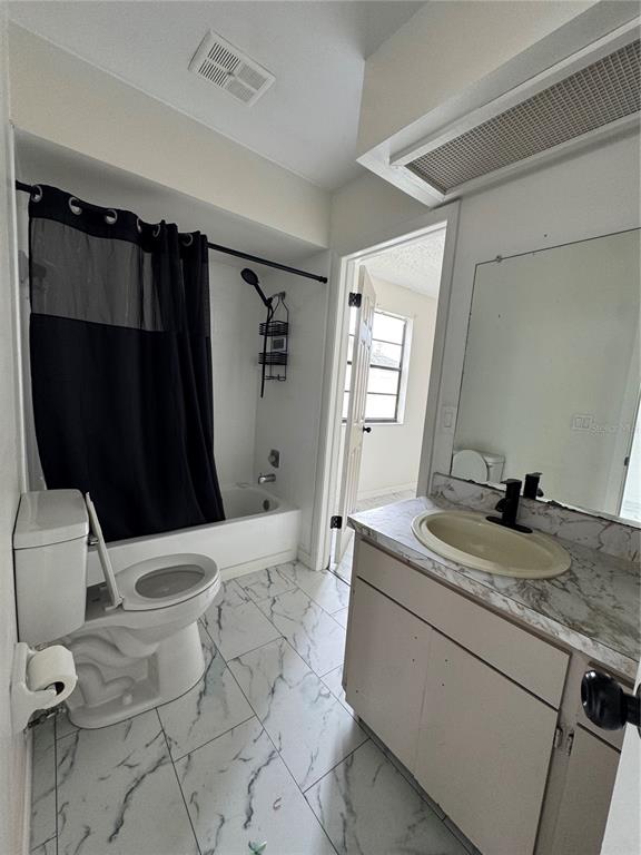 A bathroom features a white toilet, a bathtub with a black curtain, and a vanity — 10315 WALTON STREET, SPRING HILL, FL