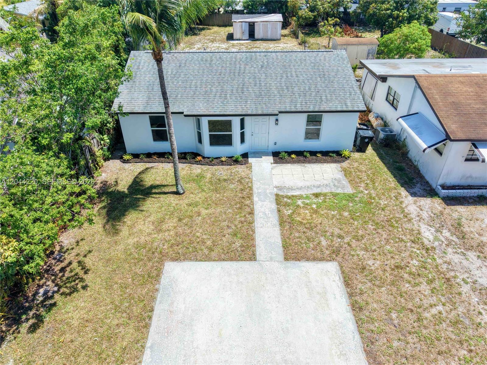 An aerial view shows a white single-story house with a gray roof and front yard — 1229 18th Ave N, Lake Worth FL 33460, LAKE WORTH, FL