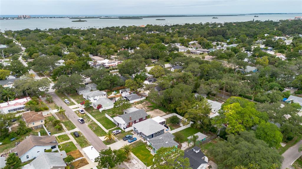 An aerial view shows a residential neighborhood with houses, trees, and a body of water — 1226 SEDEEVA CIRCLE S, CLEARWATER, FL