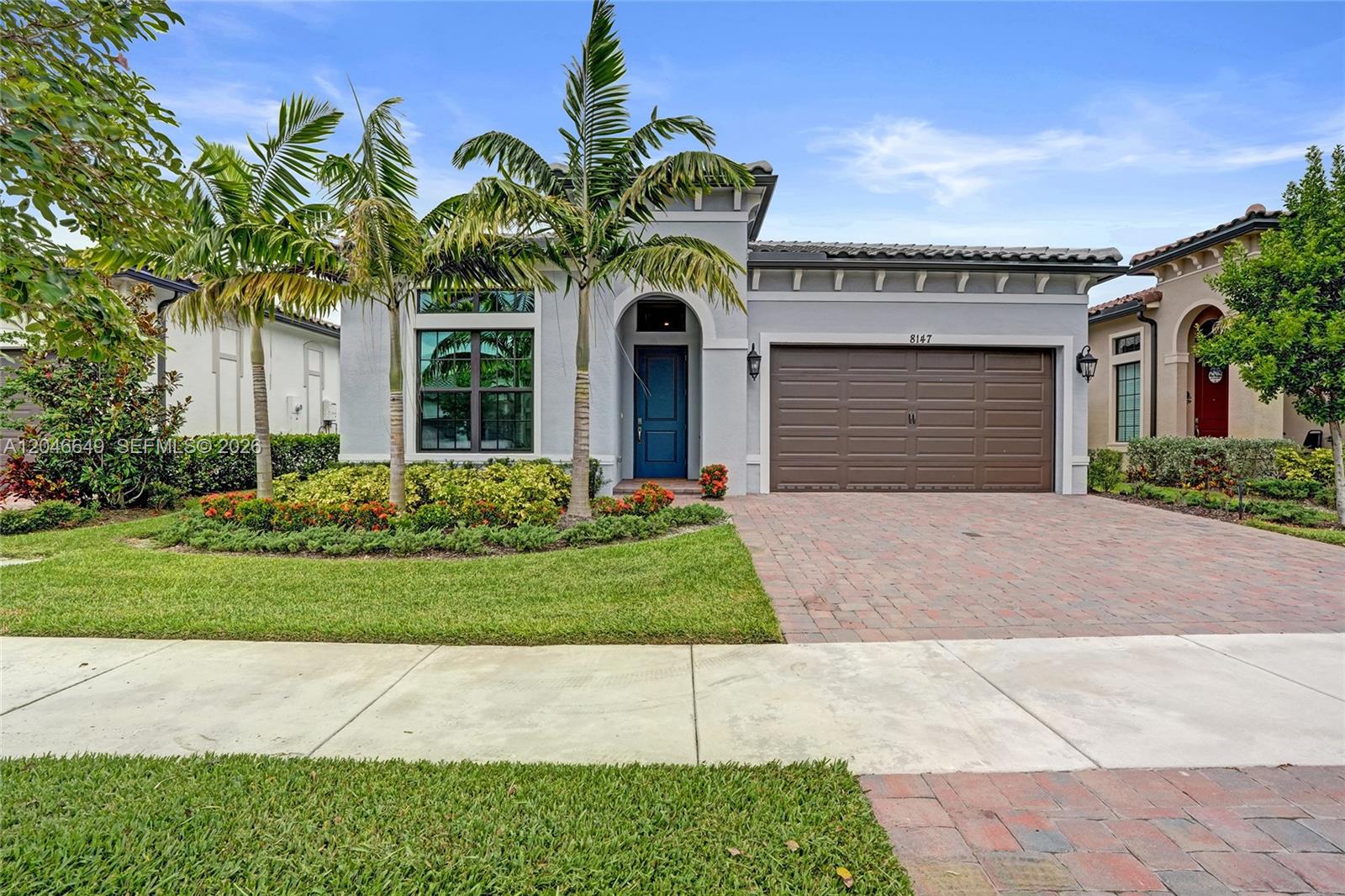 A single-story house with a gray exterior, blue front door, and a brown garage door — 8147 Juniper Dr, Parkland FL 33067, PARKLAND, FL