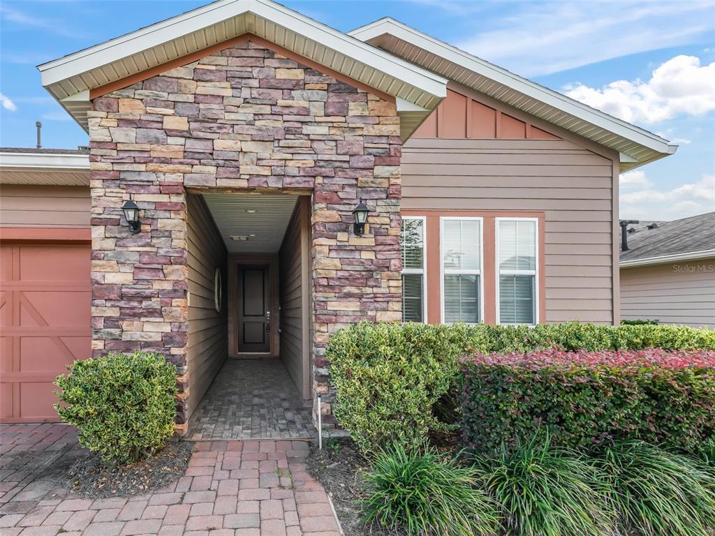 A stone-accented entryway leads to a front door with a brick paver walkway and landscaping — 4976 NW 35TH LANE ROAD, OCALA, FL