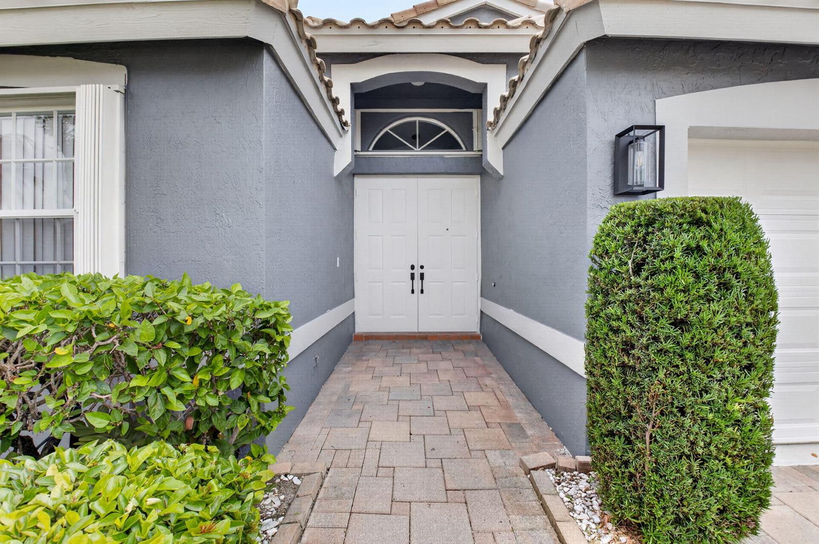 A paved walkway leads to the white double front doors of a grey stucco house — 11728 Dove Hollow Avenue, Boynton Beach FL 33437, BOYNTON BEACH, FL