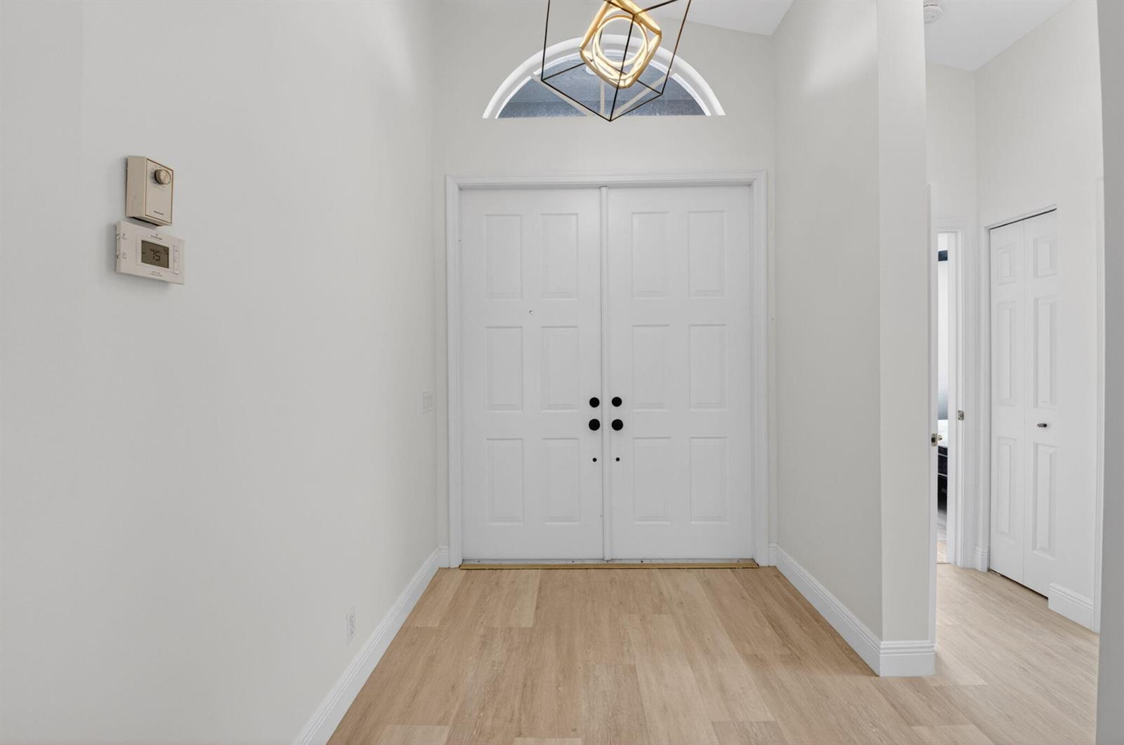 A bright entryway features double white doors, light wood flooring, and a geometric light fixture — 11728 Dove Hollow Avenue, Boynton Beach FL 33437, BOYNTON BEACH, FL