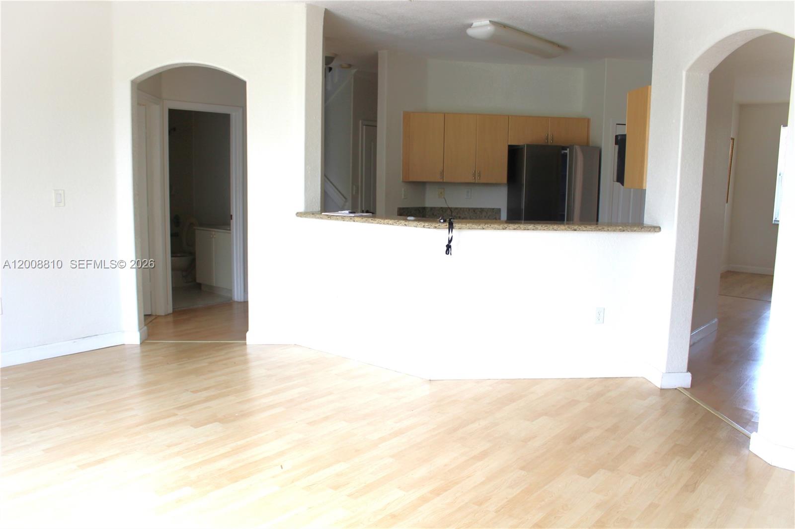 An open-concept living area features light wood flooring, a kitchen pass-through, and arched doorways — 11375 NW 77th Ln # 11375, Doral FL 33178, DORAL, FL