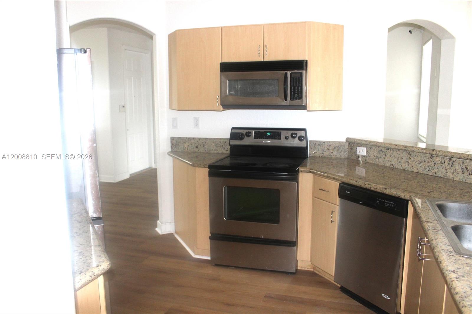 A kitchen features light wood cabinets, stainless steel appliances, and speckled granite countertops — 11375 NW 77th Ln # 11375, Doral FL 33178, DORAL, FL