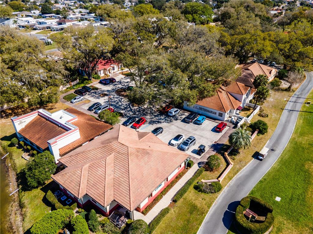 An aerial view shows two commercial buildings with tiled roofs and parking lots surrounded by trees — 309 LAGRANDE BOULEVARD, LADY LAKE, FL