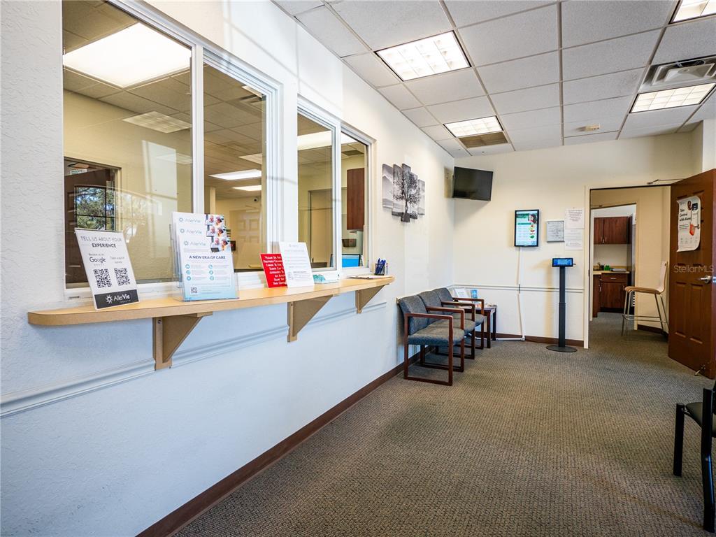 A reception area features a service window, a waiting bench, and a doorway to an office — 309 LAGRANDE BOULEVARD, LADY LAKE, FL